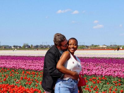 Happy interracial couple embracing in vibrant tulip fields of Lisse, Netherlands.