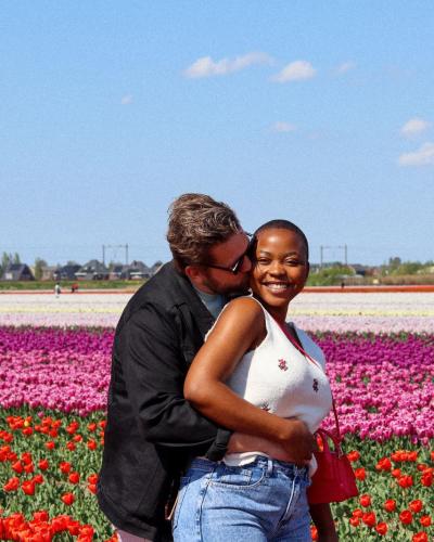 Happy interracial couple embracing in vibrant tulip fields of Lisse, Netherlands.