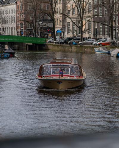 A tour boat sails through Amsterdam's historic canals surrounded by classic Dutch architecture.