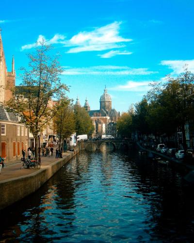 Charming view of Amsterdam's canals, architecture, and vibrant urban life under a clear blue sky.