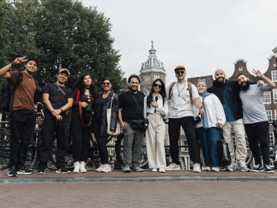 A joyful group of tourists posing in front of a scenic Amsterdam background, capturing the essence of travel and urban exploration.