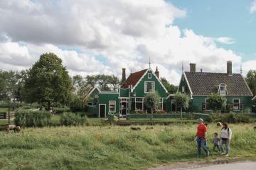 Charming Dutch houses and a family stroll in Zaanse Schans, Netherlands, showcasing traditional architecture.