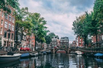 Charming view of an Amsterdam canal lined with bicycles, boats, and historic buildings.