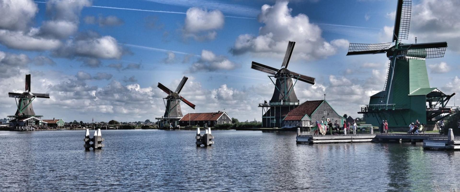 Picturesque windmills and reflections in water at Zaanse Schans, Netherlands, showcasing iconic Dutch landscape.