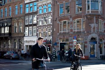 Cyclists enjoy a sunny day in Amsterdam, showcasing the city's iconic architecture.