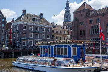 Daytime view of a canal boat and historic architecture in Amsterdam.
