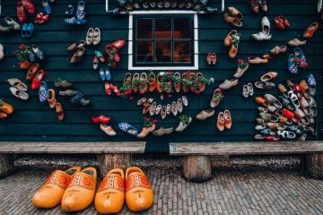 A vibrant display of colorful clogs on a traditional house wall showcases Dutch culture and design.