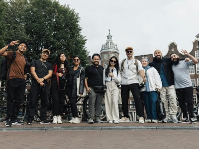 A joyful group of tourists posing in front of a scenic Amsterdam background, capturing the essence of travel and urban exploration.