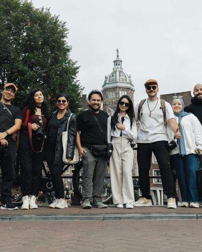 A joyful group of tourists posing in front of a scenic Amsterdam background, capturing the essence of travel and urban exploration.