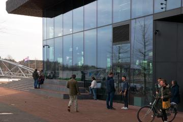 People stand outside of a modern glass building.
